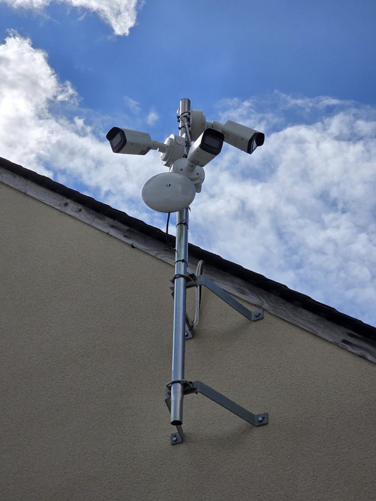 Mât équipé de plusieurs caméras thermiques et d'un pont Wi-Fi sur un parking d'entreprise